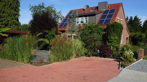 Una casa con techo inclinado, paneles solares y fachada de ladrillo.