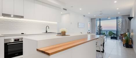 A modern kitchen with white cabinetry, a wooden countertop, and a built-in oven.