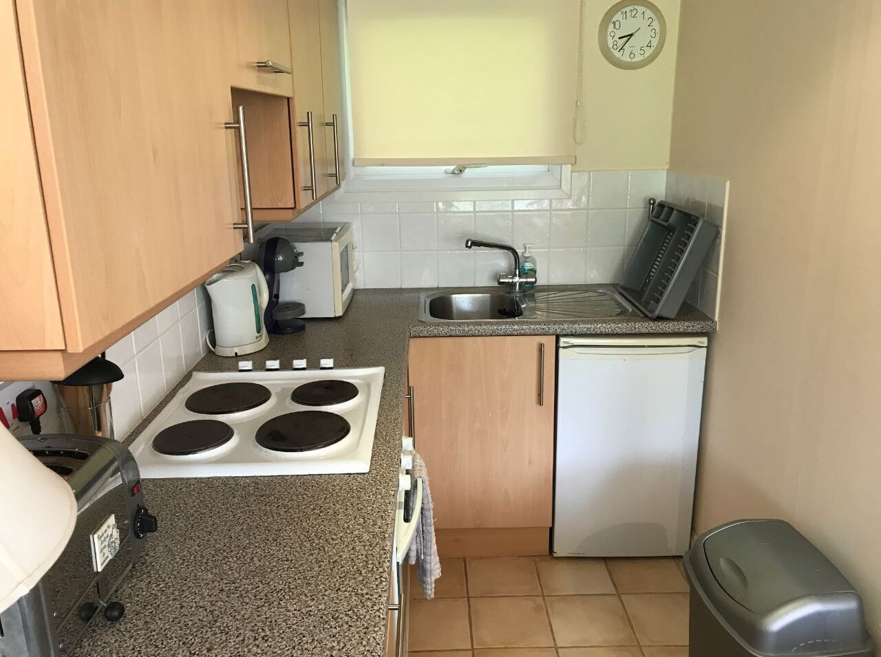 A compact kitchen with a stove, sink, and a small refrigerator.