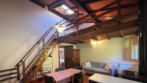 Un interior rústico con comedor, escalera y sofá.