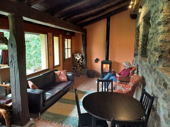 Una habitación acogedora con chimenea, un sofá, una mesa y una silla.