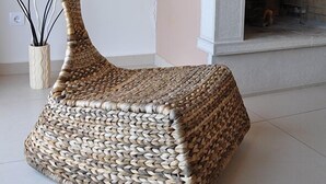 A woven pouf chair in a room with a fireplace and decorative wall art. - Porfyra's Island (Ierapetra)