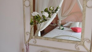 A bedroom with a bed, a bedside table, a mirror, and a vase with flowers. - Porfyra's Island (Ierapetra)