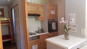 A compact kitchen with wooden cabinets, a built-in oven, and a sink. - Grand Cap 3 - Appt 4 pers in Chalet - CALM & NATURE (Tignes)