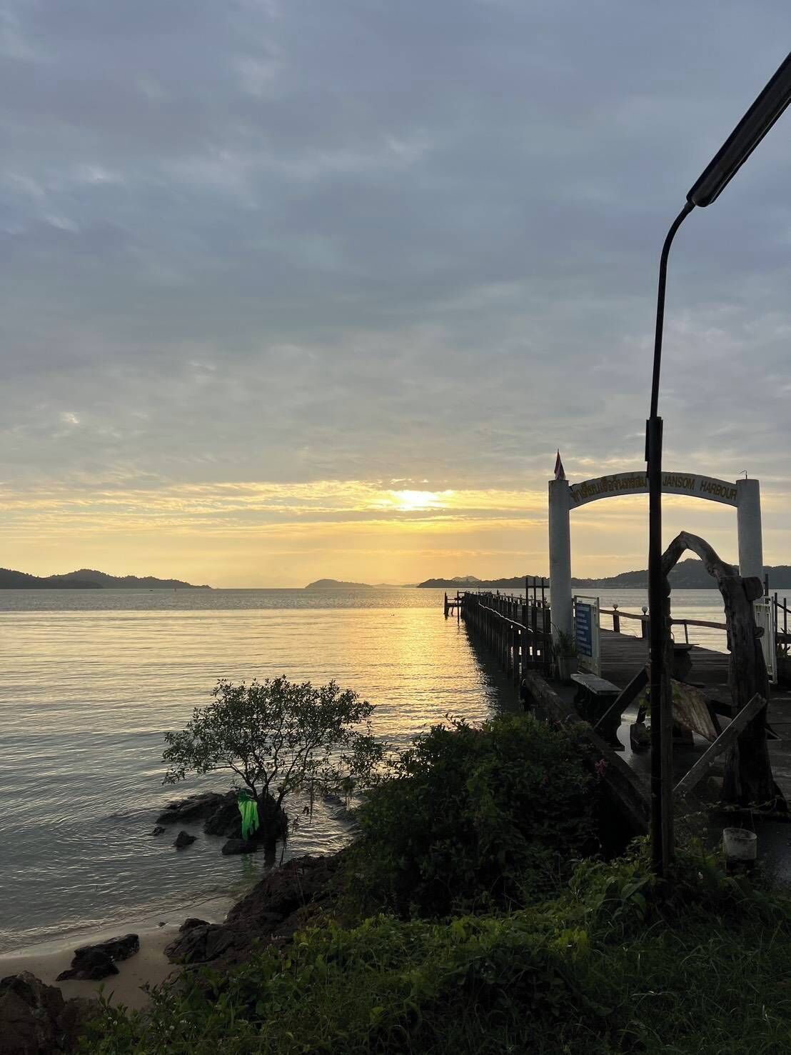 A pier extending into calm waters with a sunset in the background.