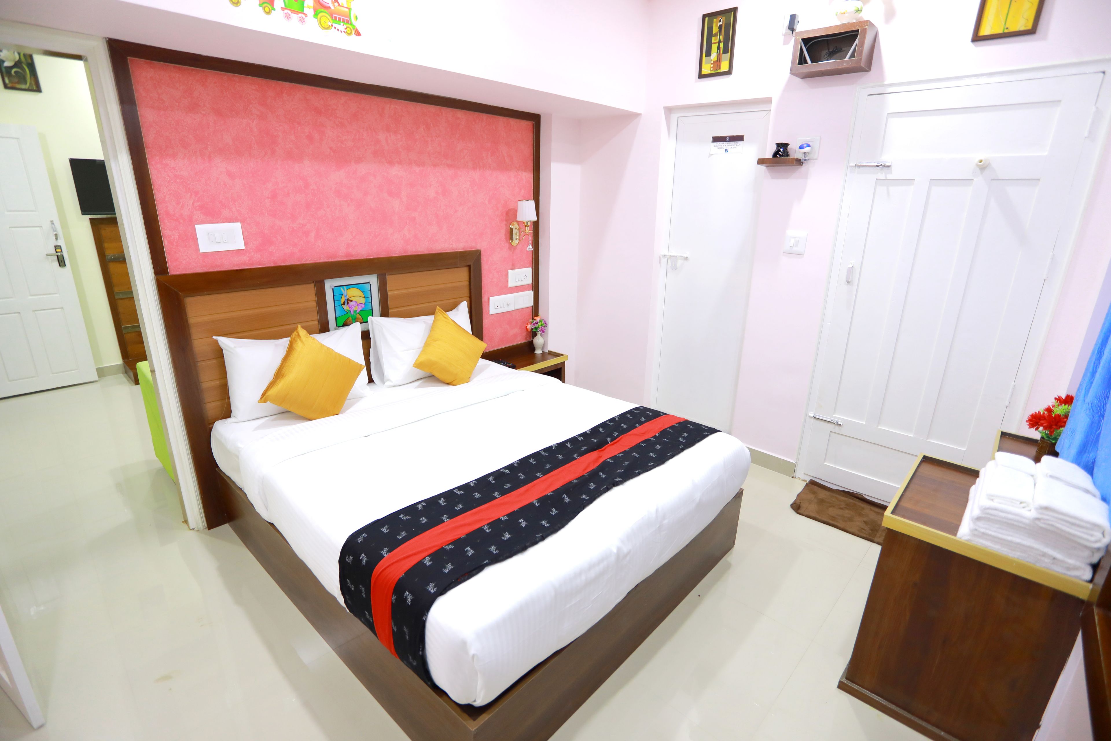 Habitación de hotel con cama, cabecera de madera, mesita de noche, armario y una pequeña mesa con toallas.