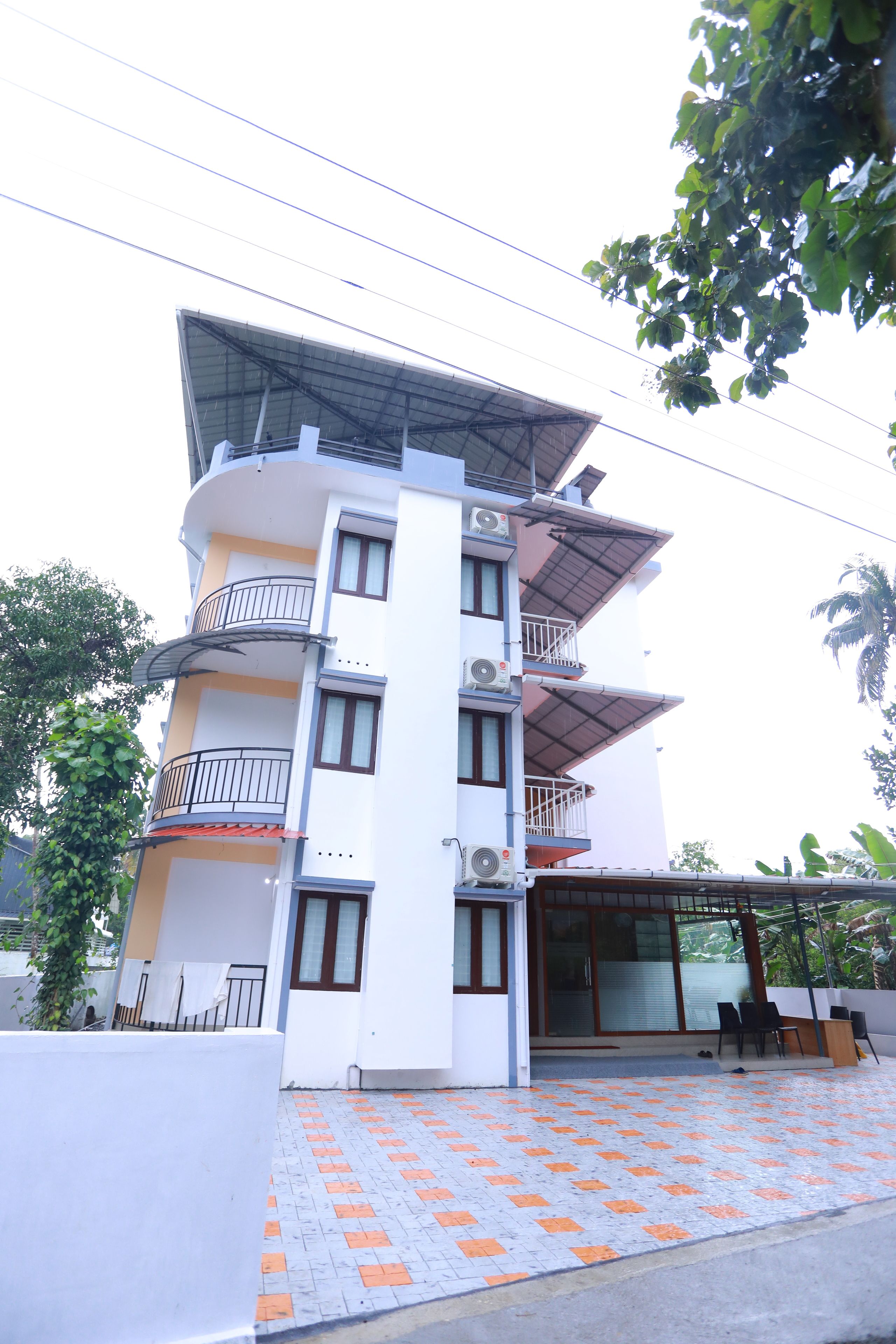 A multi-story building with balconies, air conditioning units, and a covered entrance.
