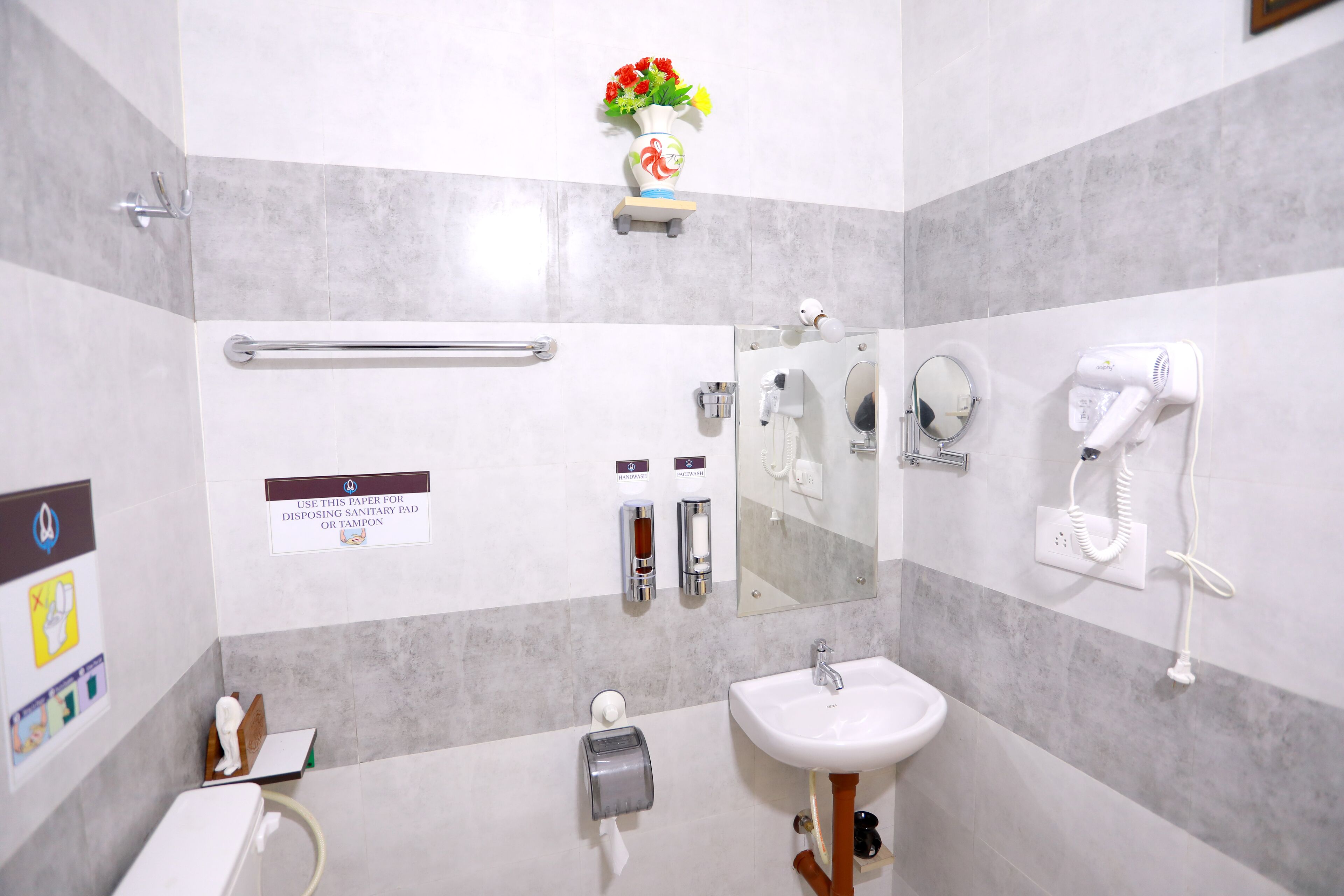 A modern bathroom with a toilet, sink, hand dryer, and paper towel dispenser.