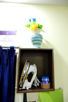 Una estantería con una tabla de planchar, un florero azul y blanco a rayas, y un letrero encima.