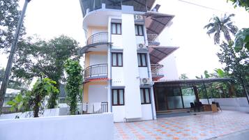 A multi-story building with balconies, a covered outdoor seating area, and a tiled patio.