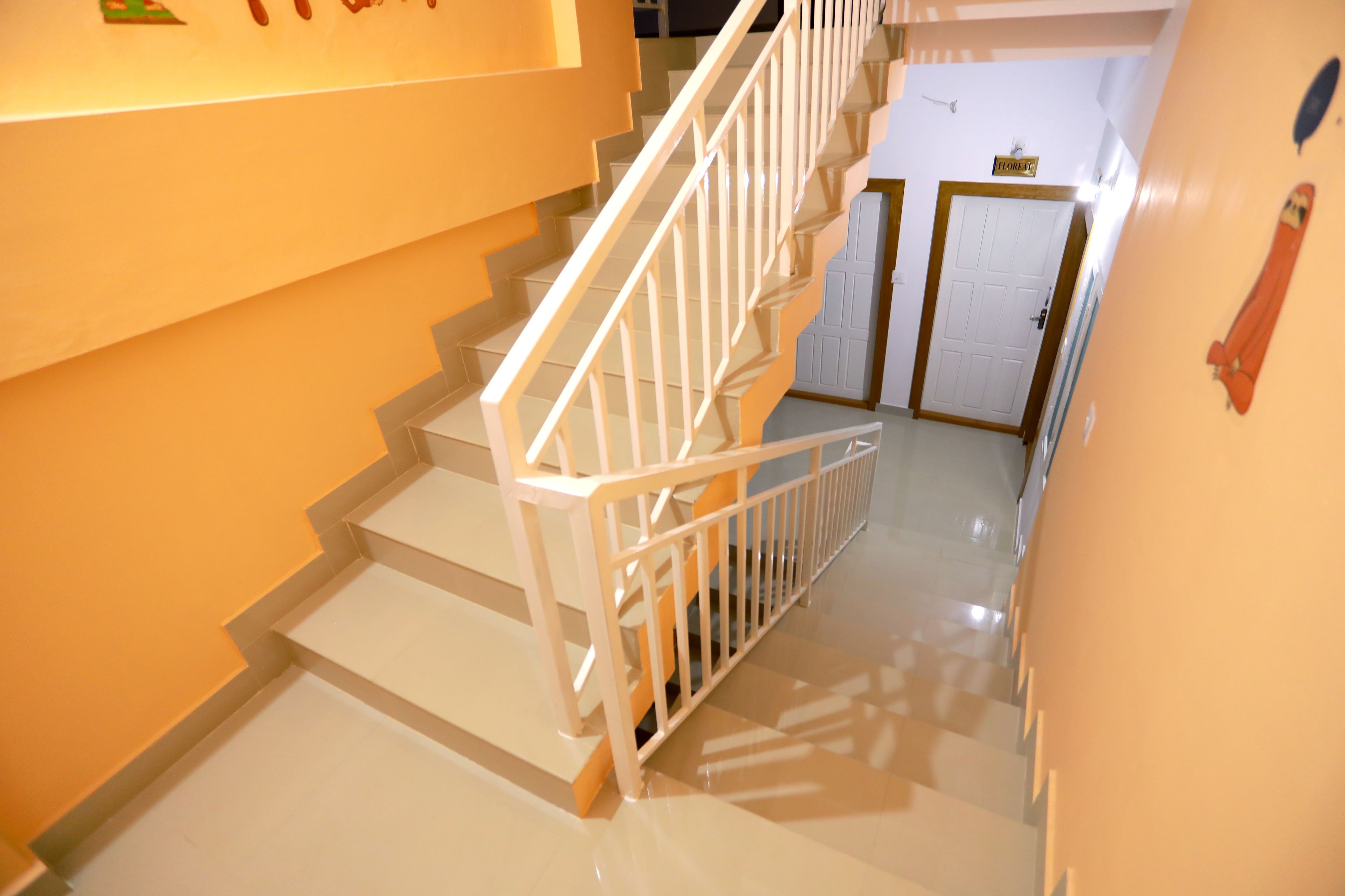 A staircase with white railings and a handrail, leading to a door labeled "TOILET".