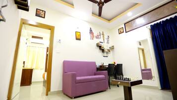 A living room with a purple sofa, a ceiling fan, and a foosball table.