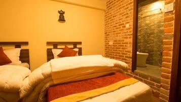 A room with two beds, a stone wall, and a window overlooking a bathroom.