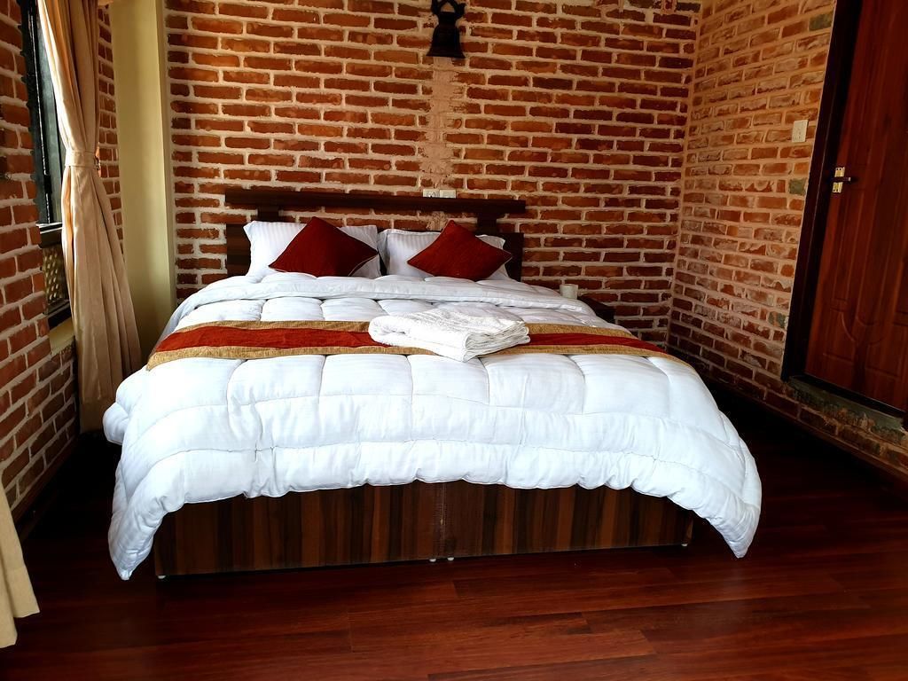 Un lit avec une tête de lit en bois, dans une pièce aux murs en briques.