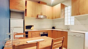 Une cuisine de taille réduite, dotée de meubles en bois, d’un four à micro-ondes, d’un évier et d’un lave-vaisselle.