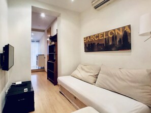 A modern living room with a sofa, a flat-screen TV mounted on the wall, and a bookshelf. - Bed&BCN Gracia II apartment in Barcelona (Barcelona)