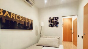 Une chambre d’hôtel comprenant un lit, un climatiseur fixé au mur, une œuvre d’art encadrée, un luminaire fixé au mur et une porte donnant sur une autre pièce.
