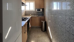 A compact kitchen with granite countertops, a microwave, and a stainless steel trash can.