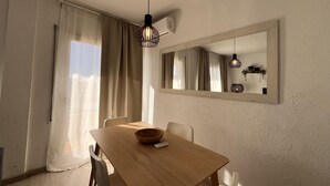 A dining area with a wooden table, chairs, a bowl, a remote control, and a hanging light fixture.