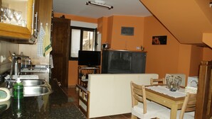 Una cocina compacta con comedor, televisión y ventana.