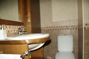 Une salle de bain avec un meuble-lavabo en bois, un évier et des toilettes.