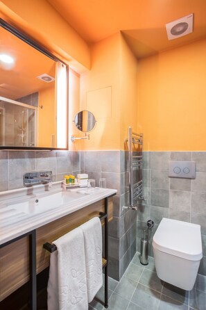 A bathroom with a white toilet, a towel rack, a mirror, and a shower area. - Signature Hotels & Spa (Ürgüp)