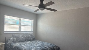 A bedroom with a bed, a nightstand, a ceiling fan, and a window with blinds. - VACATION RETREAT Madeira Beach (Madeira Beach)