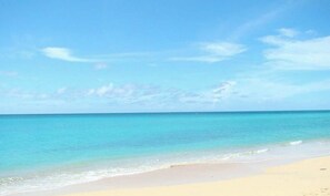 A beach with clear turquoise water and a sandy shore.