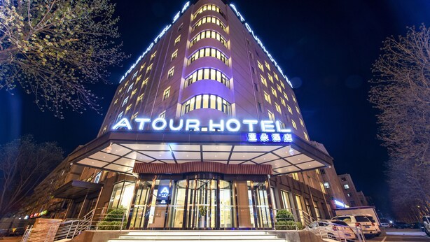 Un hotel con un letrero llamativo, varios pisos y una entrada bien iluminada.