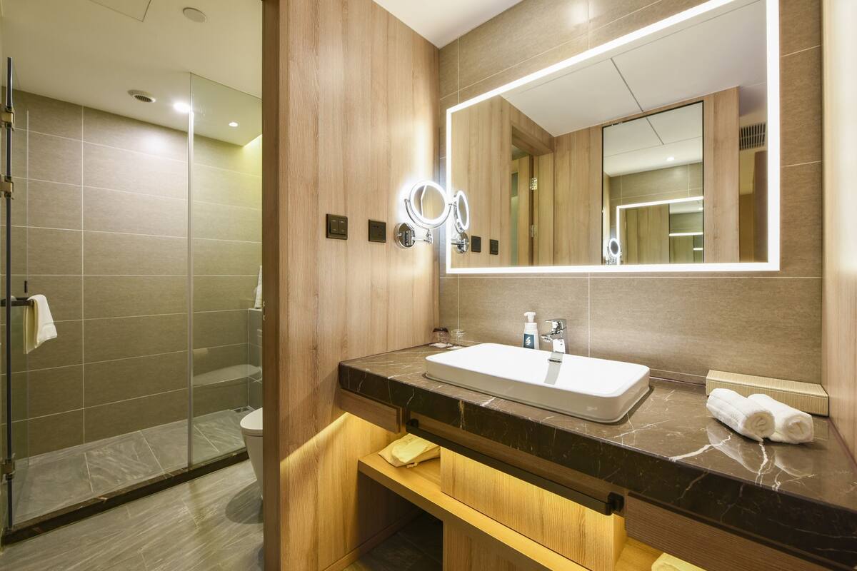 Een moderne badkamer met een grote spiegel, wastafel en douchehoek.