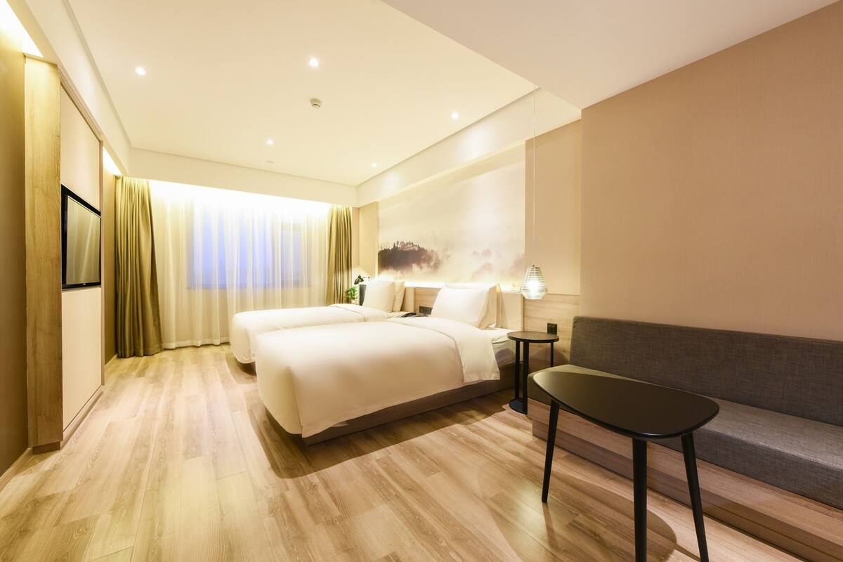 Een hotelkamer met een groot bed, een kleine tafel, een bank en een schilderij aan de muur.