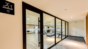 Un gimnasio moderno en un hotel, con piso de madera, puertas de vidrio y diverso equipamiento de ejercicio.