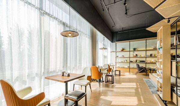 A modern interior with a large window, wooden furniture, and a bookshelf. - Atour Hotel Economic Development Zone Yangzhou (Yangzhou)
