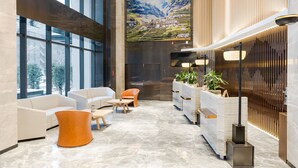 Um lobby moderno com uma grande tela de televisão, área de estar e balcão de recepção.