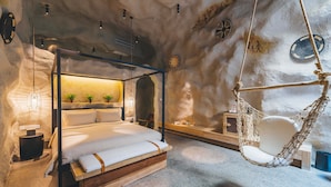 A cozy bedroom with a four-poster bed, a hanging chair, and a small bedside table.
