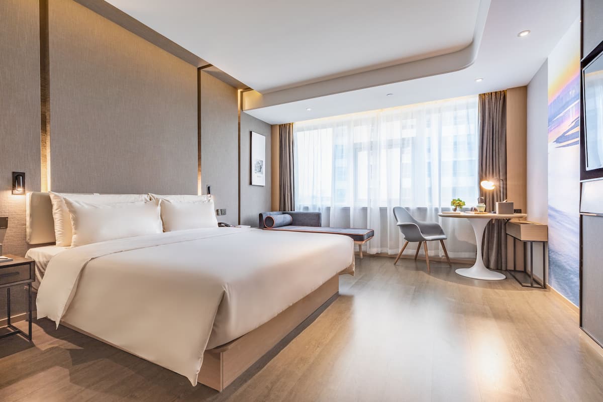 A modern hotel room with a large bed, a desk, and a chair.
