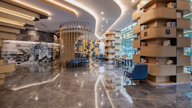 A modern interior with a curved bookshelf, seating area, and a reflective floor. - Atour Hotel Daguanyuan Jinan (Jinan)