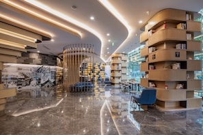 Un intérieur moderne avec une bibliothèque aux lignes courbes, un coin salon et un sol réfléchissant.