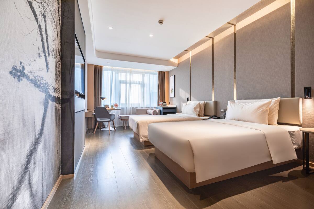 A modern hotel room with a large bed, a desk, and a chair.