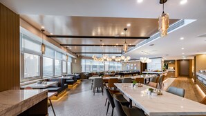 A modern restaurant with high ceilings, large windows, and a variety of seating options including tables and booths. - Atour Hotel Daguanyuan Jinan (Jinan)