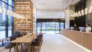 A modern reception area with a wooden reception desk, seating area with tables and chairs, and a large window offering a view of the street. - Atour Hotel Jiuyan Bridge NetEase Strict Selection Chengdu (Chengdu)