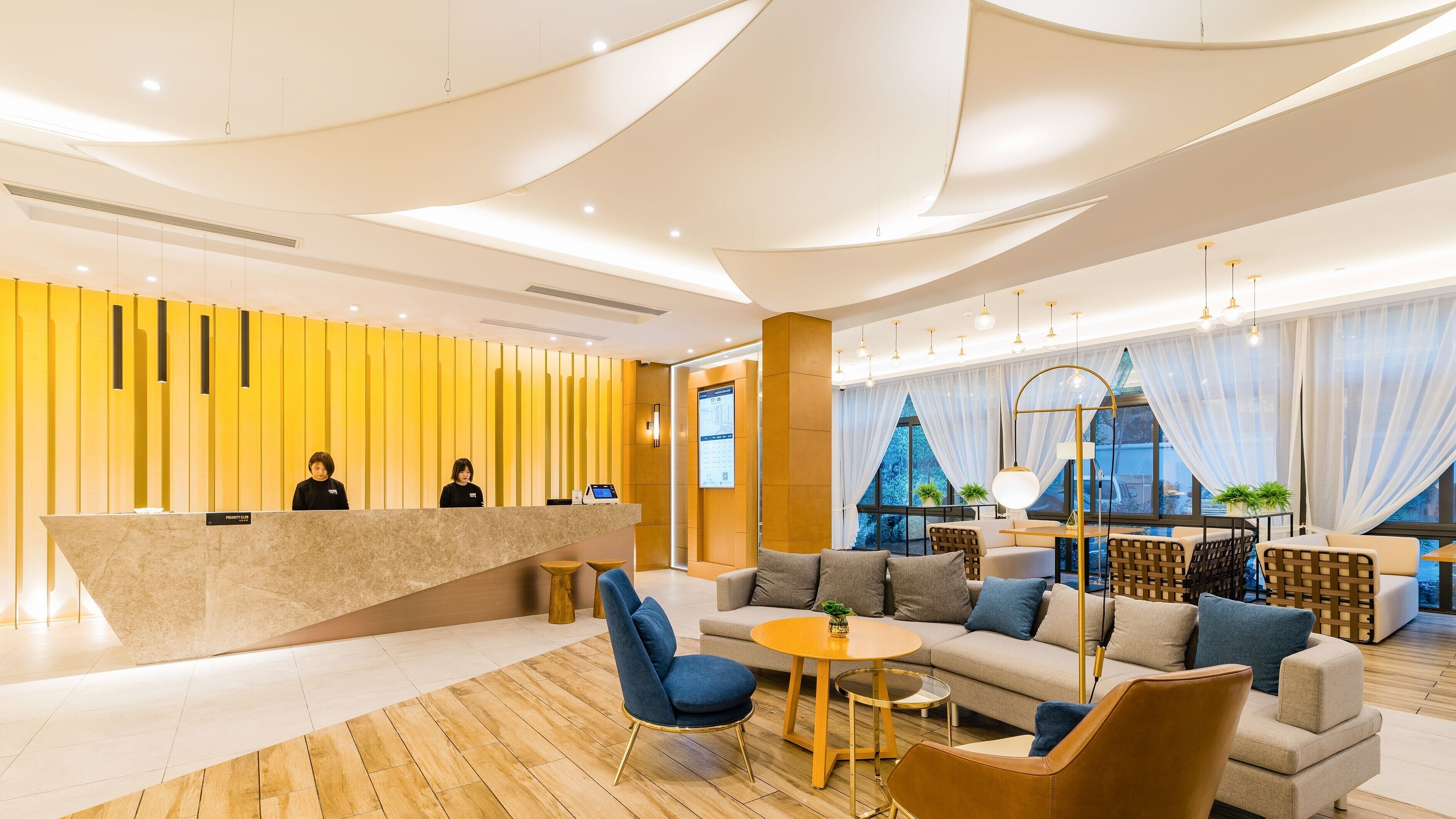 Un moderno vestíbulo de hotel con mostrador de recepción, zona de estar y grandes ventanales.