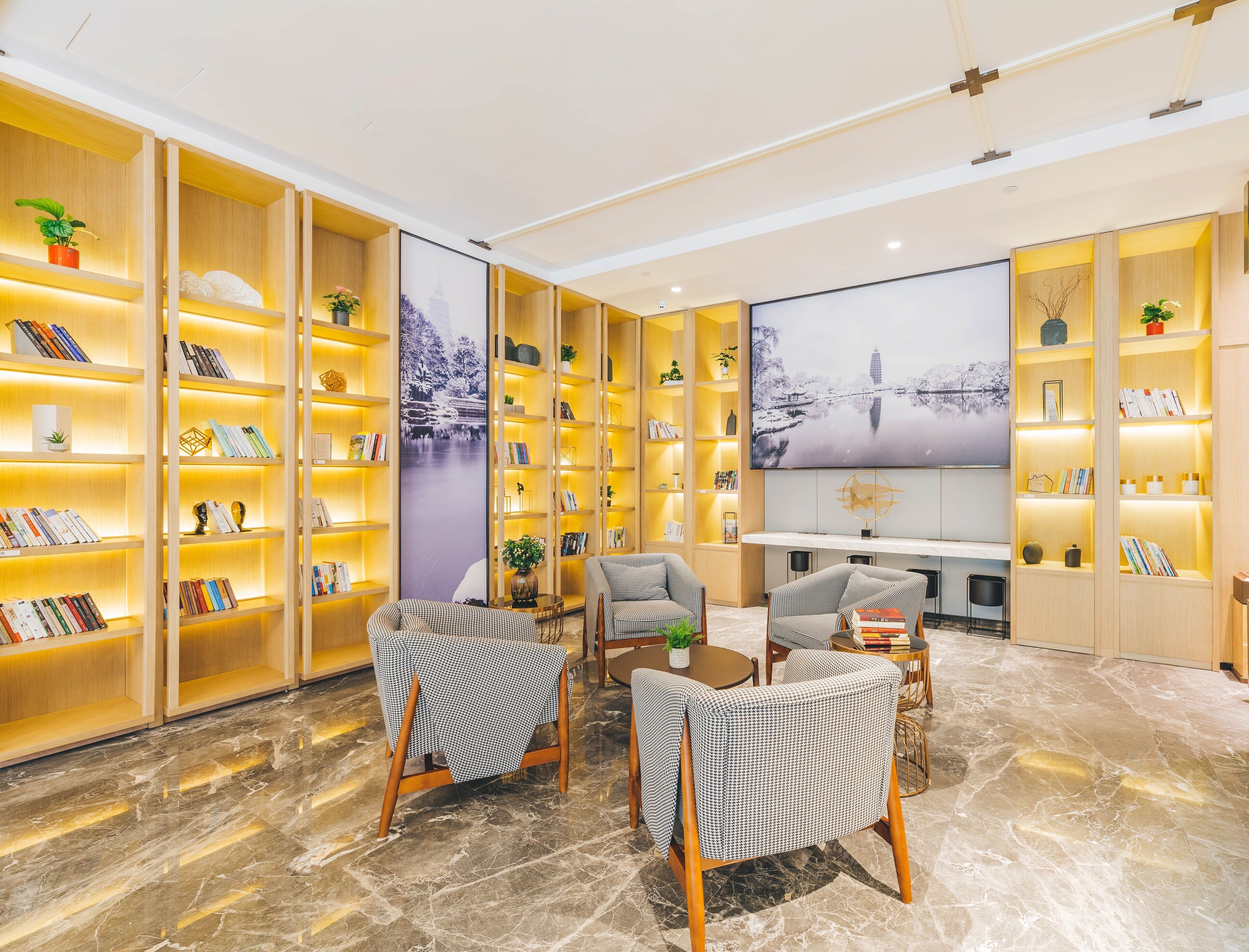A spacious reading area with multiple wooden bookshelves, comfortable seating, and a large wall-mounted TV.