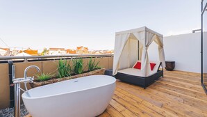 Terraço no telhado com uma banheira independente grande, uma área de estar acolchoada com toldo e vista para a paisagem urbana.