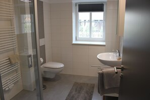 A bathroom with a toilet, sink, and glass shower enclosure. - Ferienwohnung Stall (Lübbenau/Spreewald)