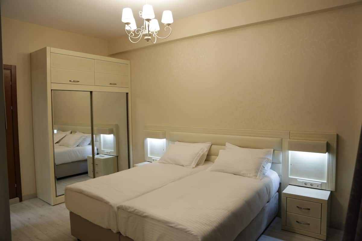 A bedroom with a large bed, a wardrobe, a nightstand, and a mirror.