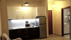 Une cuisine compacte avec des meubles blancs, un four à micro-ondes, un grille-pain et un réfrigérateur.