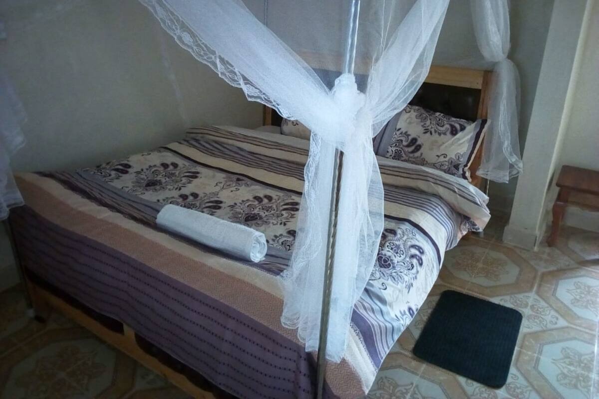 Ein Bett mit Baldachin, gemusterten Betttextilien und einem zusammengerollten Handtuch daneben.