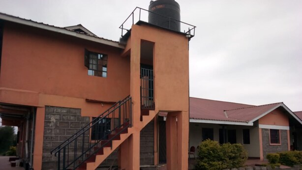 A two-story building with a central tower, a staircase, and a covered porch area. - Gee -Thorn Hotel (Chaka)
