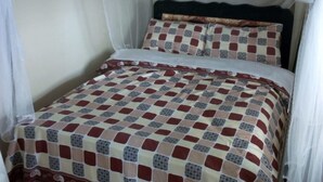 A bed with a checkered bedspread, a canopy, and a pillow with a geometric pattern. - Gee -Thorn Hotel (Chaka)